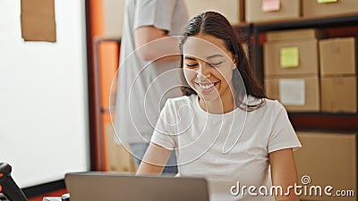 Confident team of two workers, a man and woman, laughing together while working on a laptop in the vibrant office, packaging Stock Photo