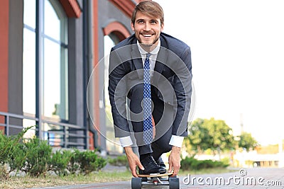 Confident young businessman in business suit on longboard hurrying to his office, on the street in the city Stock Photo