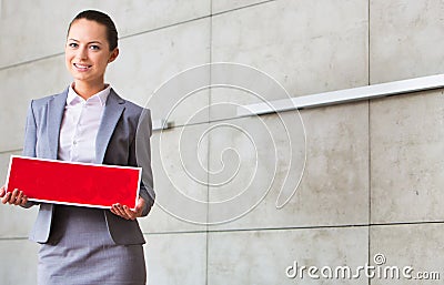 Portrait of confident young saleswoman holding sold placard while standing against wall in apartment Stock Photo