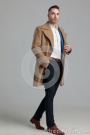 Confident young smartcasual guy in longcoat walking Stock Photo