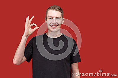 Confident young smiling man showing thumbs up OK sign and wide teeth smiles. The concept of success, joy, serenity. Stock Photo