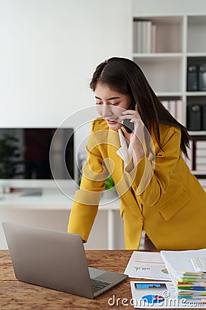 Confidently Asian business woman smiling and talking with mobile phone. Secretary checking schedule at front of boss Stock Photo