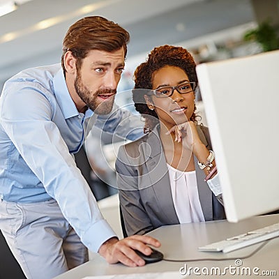 Configuring her computer settings on her first day. two coworkers using a computer together at work. Stock Photo