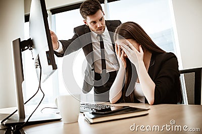 Conflict, crisis and dismissal at work. Young businessman yells at subordinate female assistant after her failure Stock Photo