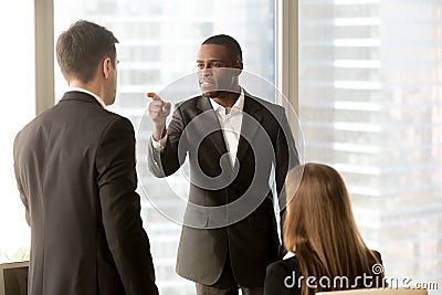 Conflict between male black and white office workers at workplac Stock Photo