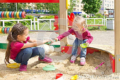 Conflict on the playground. Two kids fighting over a toy shovel in the sandbox Stock Photo