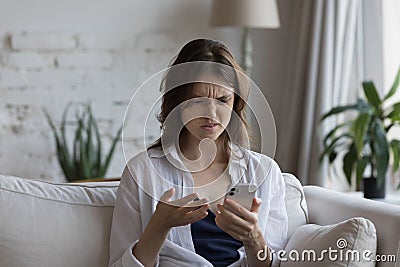 Confused annoyed customer girl using smartphone at home Stock Photo