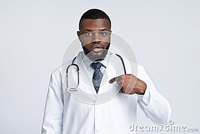 Confused black male doctor in white uniform pointing at himself Stock Photo