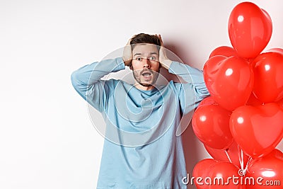 Confused boyfriend holding hands on head and panicking on Valentines holiday, alarmed with romantic presents on lovers Stock Photo