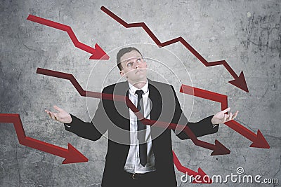 Confused caucasian businessman against declining charts background Stock Photo