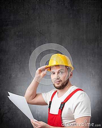 A confused construction worker holding papers or documents Stock Photo