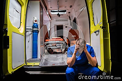 Confused corpsman in blue uniform sit on the ambulance car Stock Photo