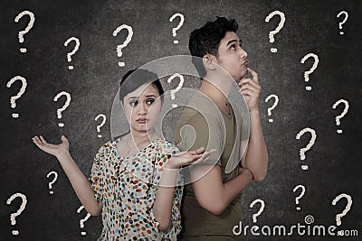 Confused couple with question marks on blackboard Stock Photo