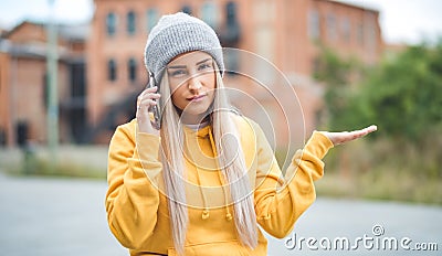 Confused cute woman on the mobile phone. Outdoors daylight. Female with smartphone. Nuisance concept Stock Photo