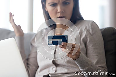 Confused female customer holding credit card angry with online payment Stock Photo