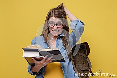 Confused female student with a pile of books rubbing her head troubled with exam Stock Photo