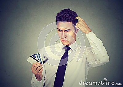 Confused man looking at many credit cards uncertain which one to choose Stock Photo