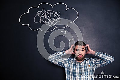 Confused man thinking about problem with black board behind him Stock Photo