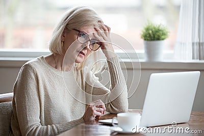 Confused mature woman thinking about online problem looking at l Stock Photo