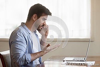 Frustrated man talk on cell having laptop problems Stock Photo