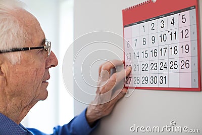 Confused Senior Man With Dementia Looking At Wall Calendar Stock Photo