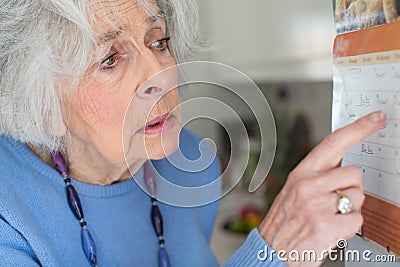 Confused Senior Woman With Dementia Looking At Wall Calendar Stock Photo