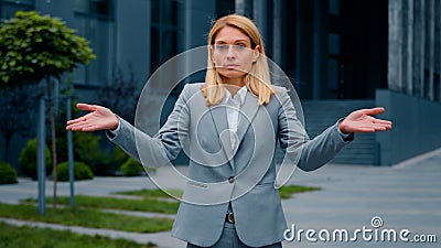 Confused serious pensive puzzled businesswoman standing outdoors spreads arms shrugs unsure caucasian woman doesn't Stock Photo