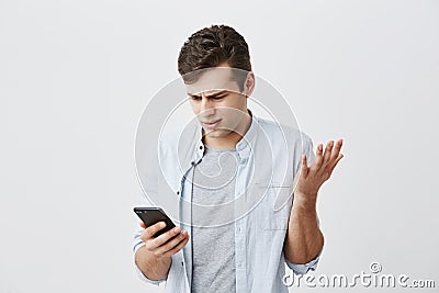 Confused shocked emotional young caucasian male student having puzzled expression after recieving message, looking at Stock Photo