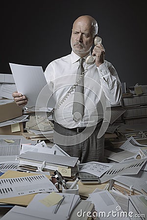 Confused stressed office worker answering phone calls Stock Photo