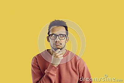 Confused student in glasses doubting something and thinking hard with hand on his chin Stock Photo