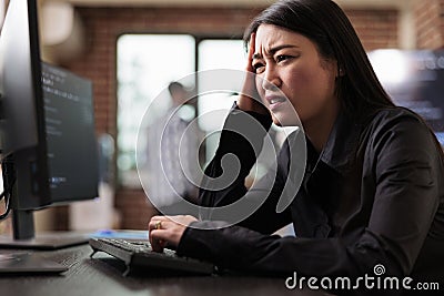 Confused tech engineer sitting at computer trying to solve network processing errors. Stock Photo