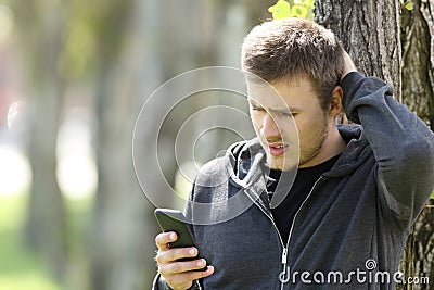 Confused teen reading message in a smart phone Stock Photo