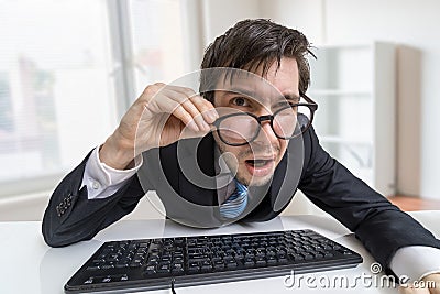 Confused or unsure man is working with computer and looking at you Stock Photo