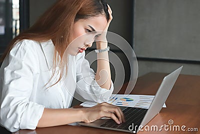 Confused upset young Asian business woman suffering from severe from depression in workplace. Stock Photo