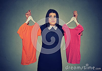 Confused woman choosing between dresses and can not make decision. Stock Photo