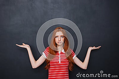 Confused woman holding copyspace on both palms over chalkboard background Stock Photo