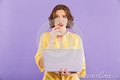 Confused woman isolated over purple wall background using laptop computer. Stock Photo