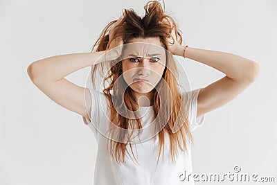 Confused woman in t-shirt holding hair and looking at camera Stock Photo