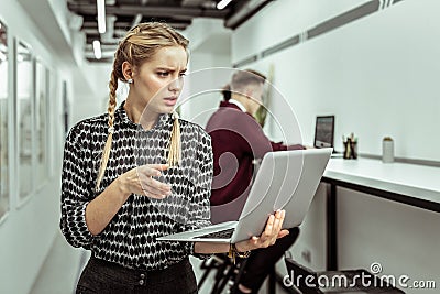 Confused woman with two braids looking nonplussed while dealing with work aspects Stock Photo