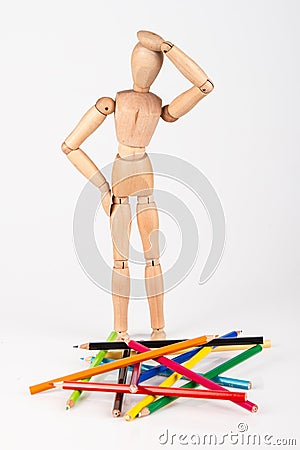 Confused wood mannequin standing at heap of colour pencil isolated on white Stock Photo