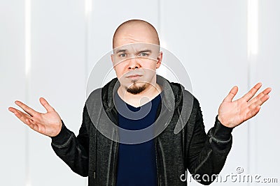 Confused young bald man with alopecia shrugs Stock Photo