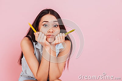 Confused young woman holding crayons and looking at camera Stock Photo