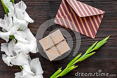 Congratulation. Envelope and box in kraft paper near flower gladiolus on wooden table top view Stock Photo