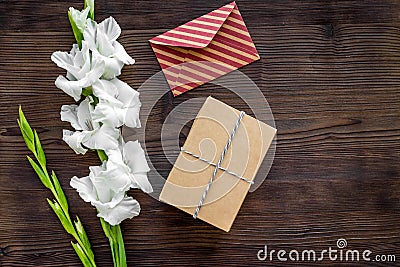 Congratulation. Envelope and box in kraft paper near flower gladiolus on wooden table top view copyspace Stock Photo