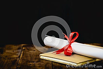 Congratulations for graduating.mortarboard and graduation scroll,tied with red ribbon, on a stack of old battered book with copy s Stock Photo