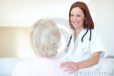 A conscientious checkup on an adored patient. Friendly mature nurse comforts her elderly patient with a hand to the Stock Photo