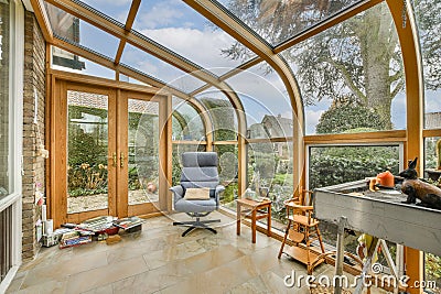 a conservatory with large glass windows and a chair Editorial Stock Photo