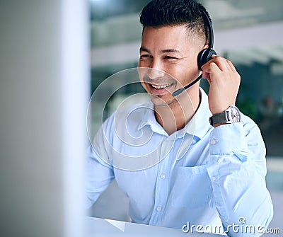 Consistent care keeps customers on the line. a young man using a headset and computer in a modern office. Stock Photo