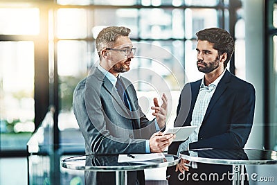 Consolidating their ideas with smart apps. two colleagues using a digital tablet together in a modern office. Stock Photo
