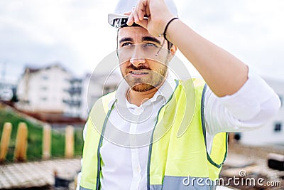 architect working on construction site, wearing hard hat and safety vest Stock Photo